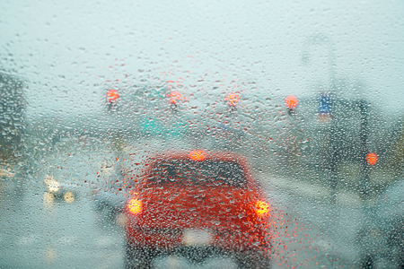 blurred street scene through car windows with rain dropの写真素材
