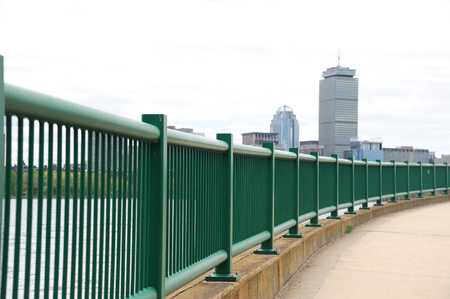 perspective view of railing on river bank in city with downtown skylineの写真素材