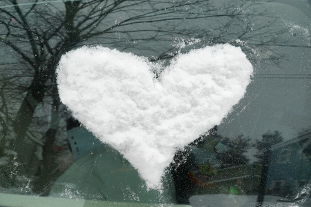 snow in heart shape on windshield of the carの写真素材