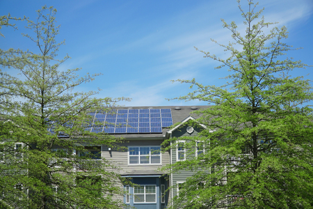 apartment building with solar panel installed on roof after green trees