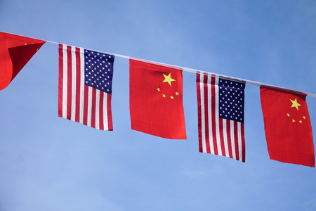 USA and China flags hanging under blue skyの写真素材
