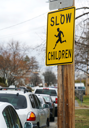 warning sign post on street pole to slow for children