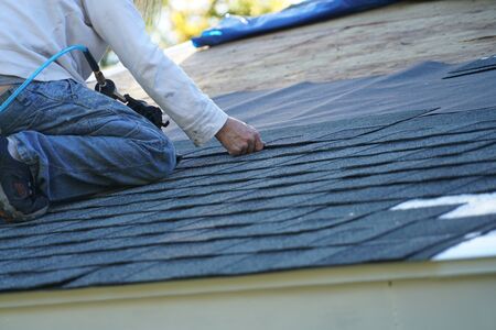 worker install new shingle on the roof of the house for roof repairの写真素材