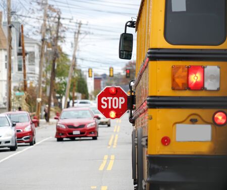 school bus with stop sign flashing on the streetの写真素材