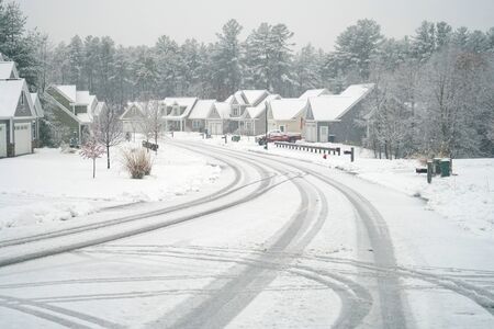 houses on both sides of street in residential community after snow in winterの写真素材