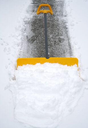 close up on snow shovel removing snow on the drivewayの写真素材