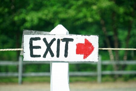 exit and arrow sign outdoor in front of treesの写真素材
