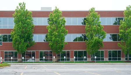 facade view of office building with green trees in frontの写真素材