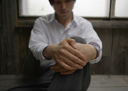 Man sitting with arms around kneeの写真素材
