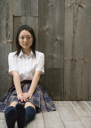 Girl sitting on floor in school uniformの写真素材