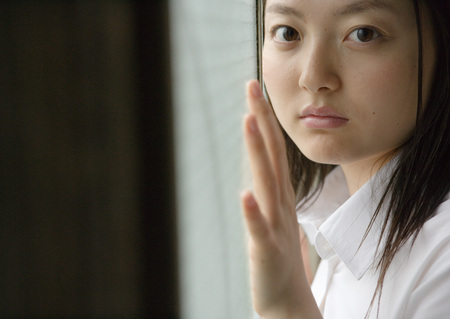Girl by window in school uniformの写真素材