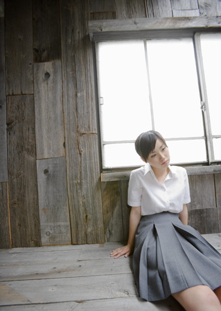 Girl sitting by window in school uniformの写真素材