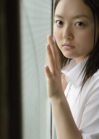 Girl by window in school uniformの写真素材