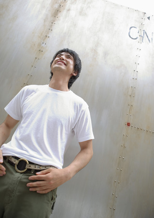Young man standing by wallの写真素材