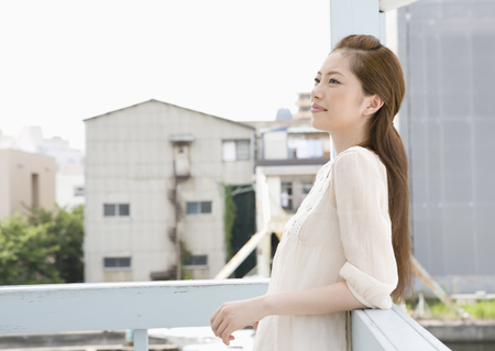 Young woman leaning on railingの写真素材