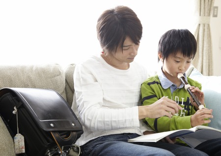 Son practicing recorder with fatherの写真素材