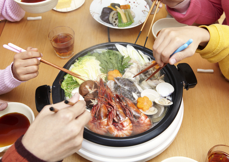 Family's hands sitting around yosenabeの写真素材