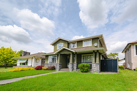 Main entrance of residential house with concrete pathway over green lawn of the front yard on cloudy sky backgroundの写真素材