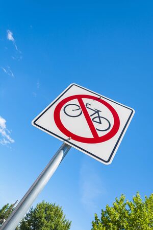Road sign no bike and tops of trees on blue sky backgroundの写真素材
