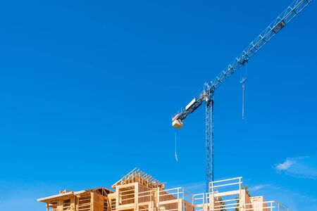 New building construction with the crane above its top on blue sky background