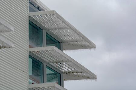 Icicles of freezing rain over weather shelds of an office buildingの写真素材