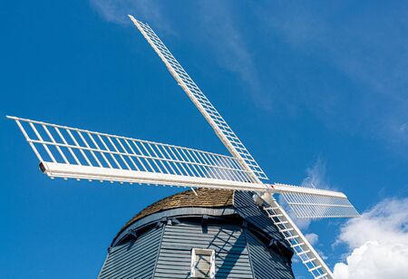 Top of vintage wind mill decorated with lights on blue sky background.の写真素材
