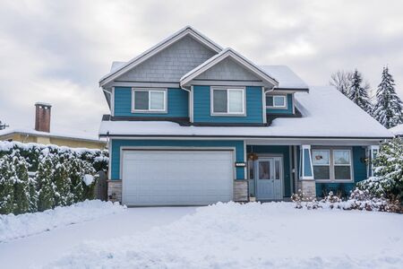 Family house with front yard in snow. Residential house on winter cloudy dayの写真素材