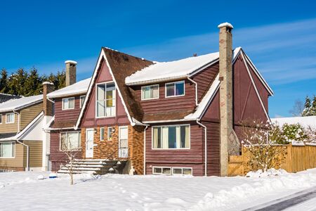 Modest residential duplex house with asphalt driveway and front yard in snow on sunny winter dayの写真素材