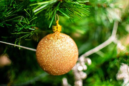 Gold bauble among chistmas tree brenches. Closeup look of the ballの写真素材