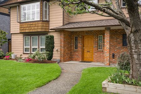 Nice main entrance of old family house with brick textured wall and concrete pathway over front yard...