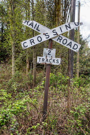Old sign of railroad crossing on spring trees backgroundの写真素材