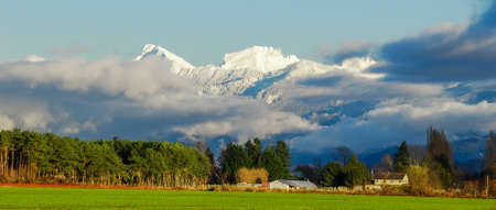 Pastoral overview over Fraser valley farm lands on snowy mountains backgroundの写真素材