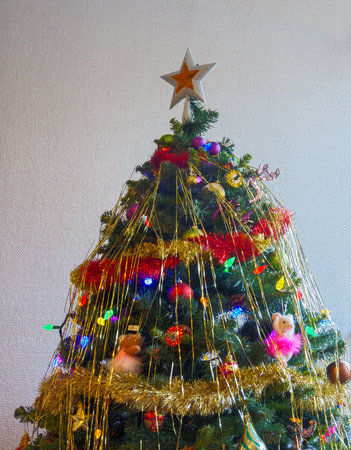 White-golden star and colourful balls with color electtric lights decorating top of Christmas tree