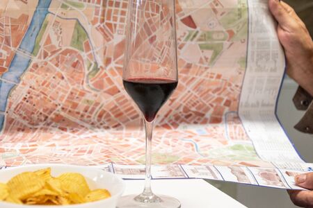 Wine glass with city map in the hands of man having snack planning tripの写真素材