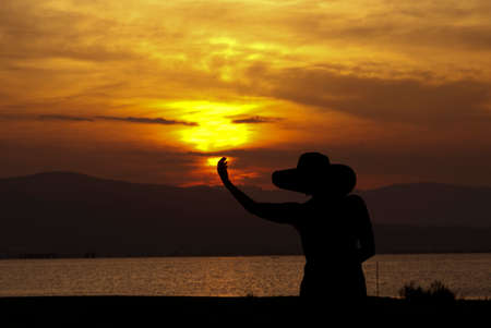Woman in hat backlit with sunset sunsetの写真素材