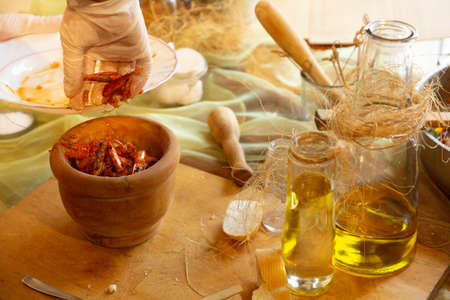 Womans hands with gloves cooking squid in sauce, pounding prawn heads in mortarの写真素材