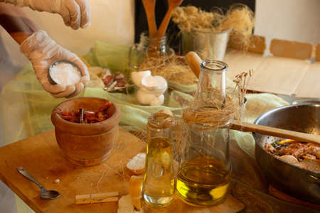 Womans hands with gloves cooking squid in sauce, pounding prawn heads in mortarの写真素材