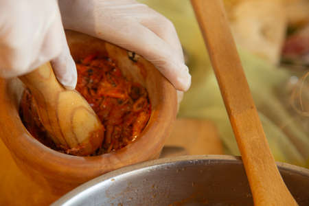 Womans hands with gloves cooking squid in sauce, mashing prawn headsの写真素材