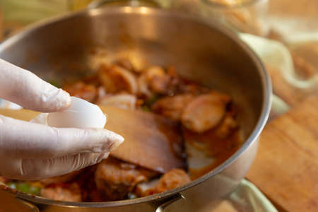 Womans hands with gloves cooking squid in sauce, mashing prawn headsの写真素材
