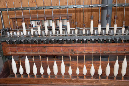 Old loom, spinning machine, rows of white and colored cotton threadsの写真素材