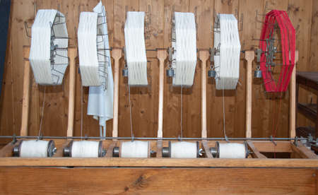 Old loom, spinning machine, rows of white and colored cotton threads