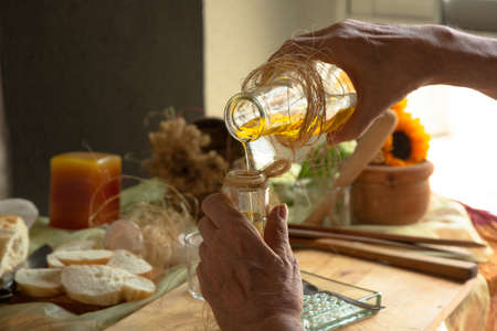 Cropped image of woman holding glass bottle of olive oil in hands isolated on white