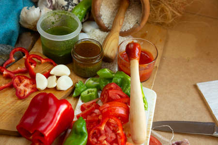 Red pepper cut with kitchen knife and split tomato on wooden boardの写真素材