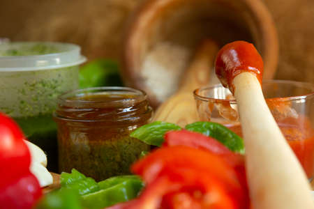 Red pepper cut with kitchen knife and split tomato on wooden boardの写真素材