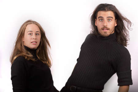 Young and beautiful blonde woman in black sweater and a handsome man in black sweater both making comic gestures on white backgroundの写真素材