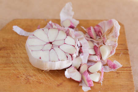 Head of garlic split in half on wooden board in the kitchenの写真素材