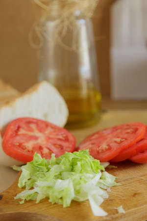 Hamburger preparation with tomato and lettuce on wooden boardの写真素材