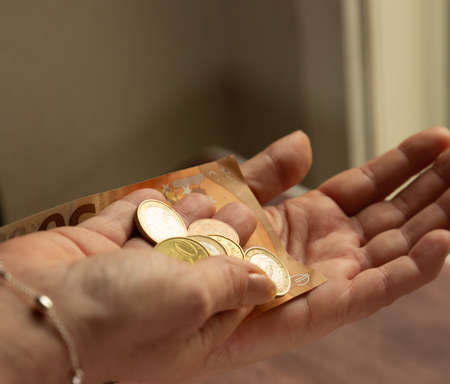 Womans hands with loose euro coins to pay in cash