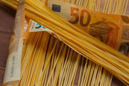 Coins and paper money on pasta, concept of rising prices in agriculture