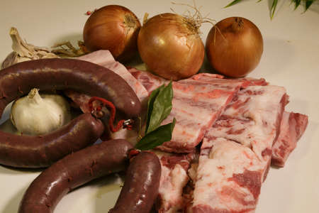 food ingredients with homemade chorizo, black pudding, onions and meat on the tableの写真素材
